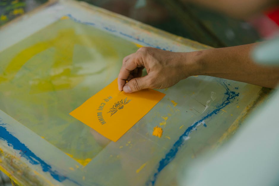 A person is using a yellow paper to make a print